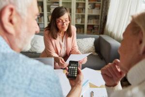 Älteres Paar mit Taschenrechner, das über ein Angebot nachdenkt, um bei einer Finanzberatung Geld zu sparen