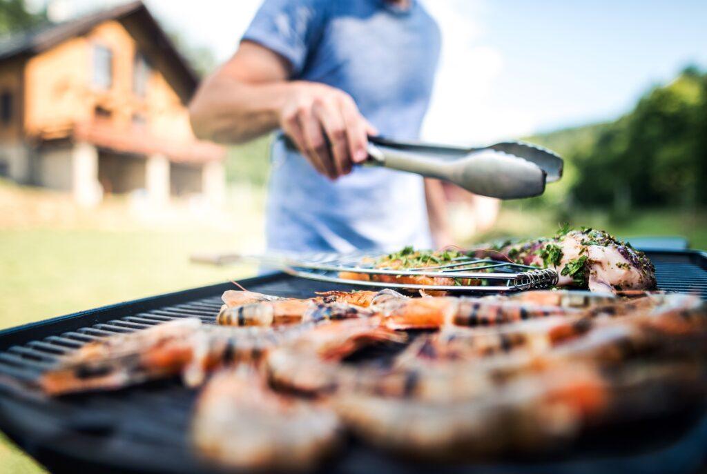 Mann grillt Fleisch und Garnelen im Garten | Outdoor Küche